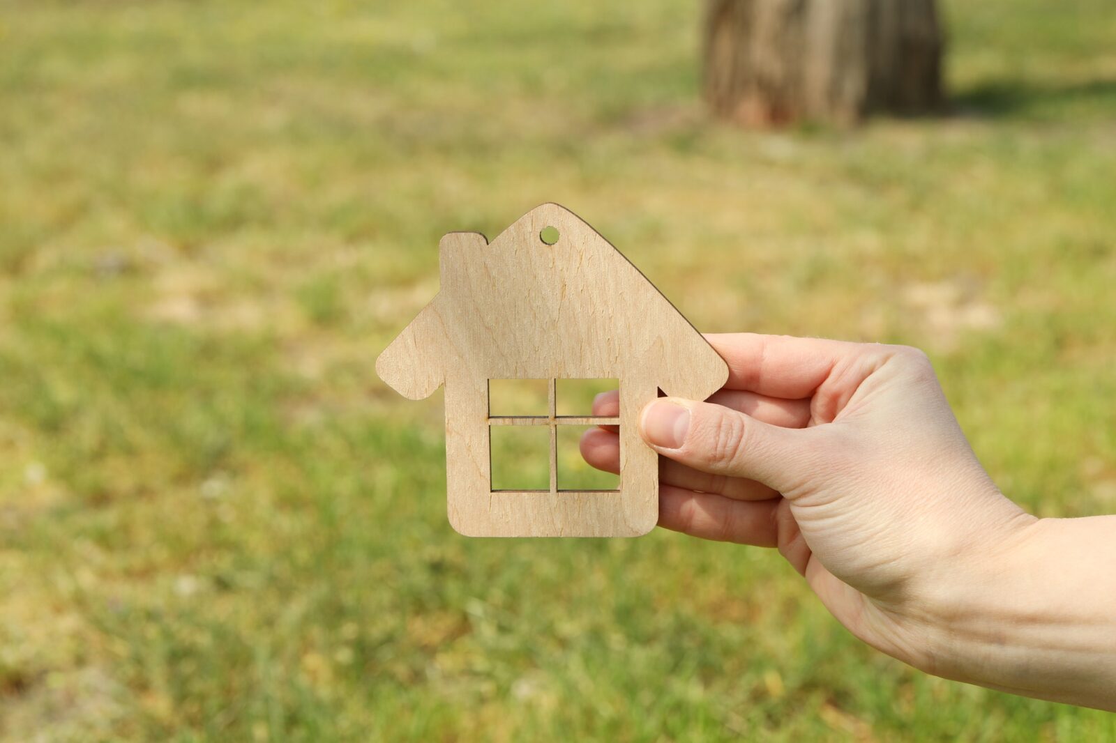 Female hand holds wooden house. Buying a property