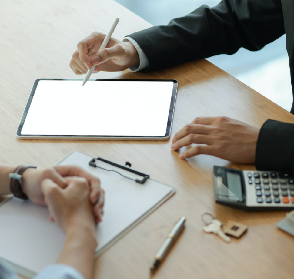 Insurance agents with tablet are introducing real estate insurance programs for customer.